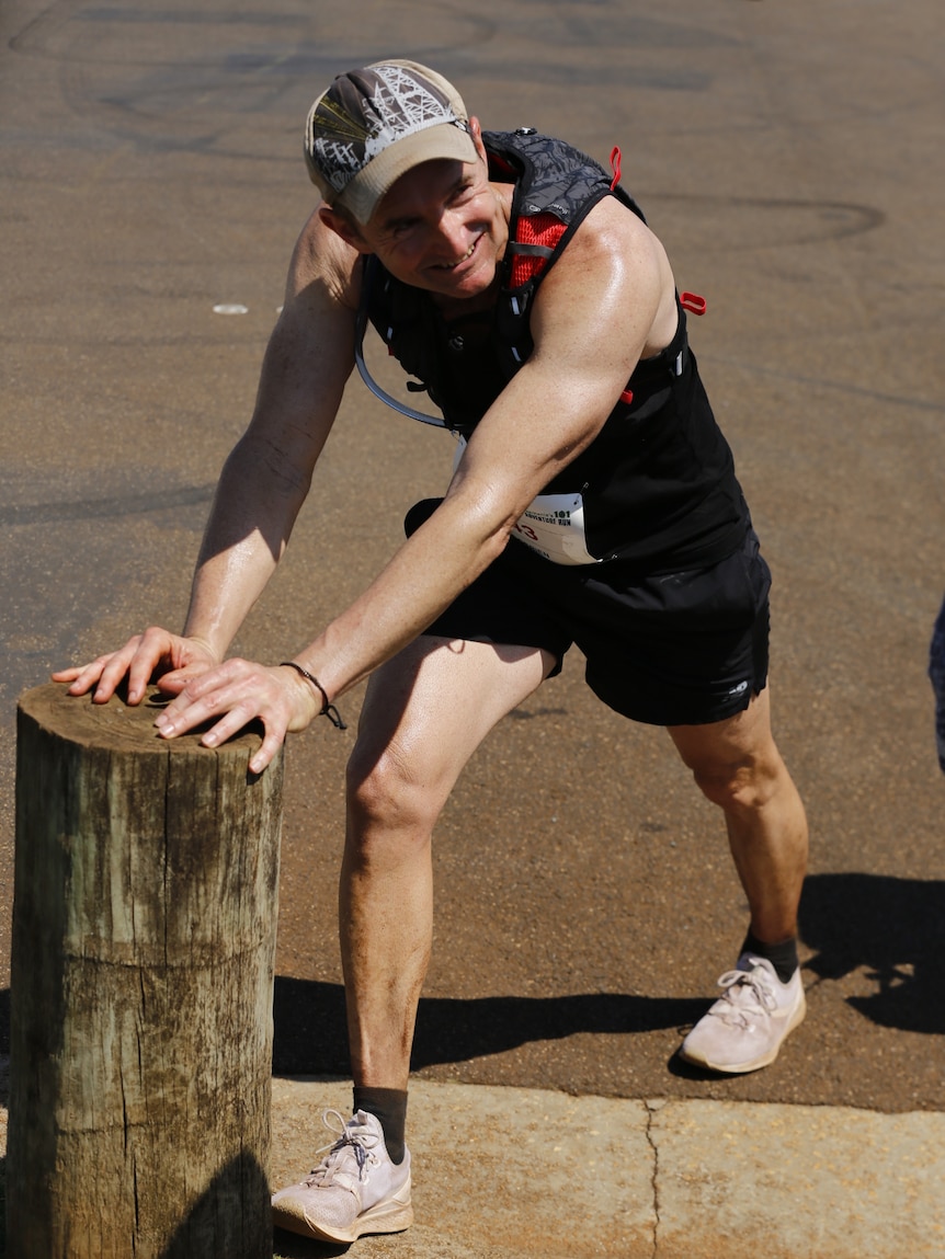 O'Brien stretching calves while leaning on post.