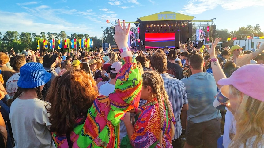 A woman with her hand up in a crowd at a musical festival. 