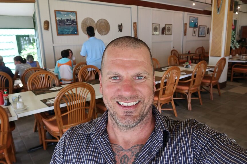 A middle aged man does a selfie in a restaurant.