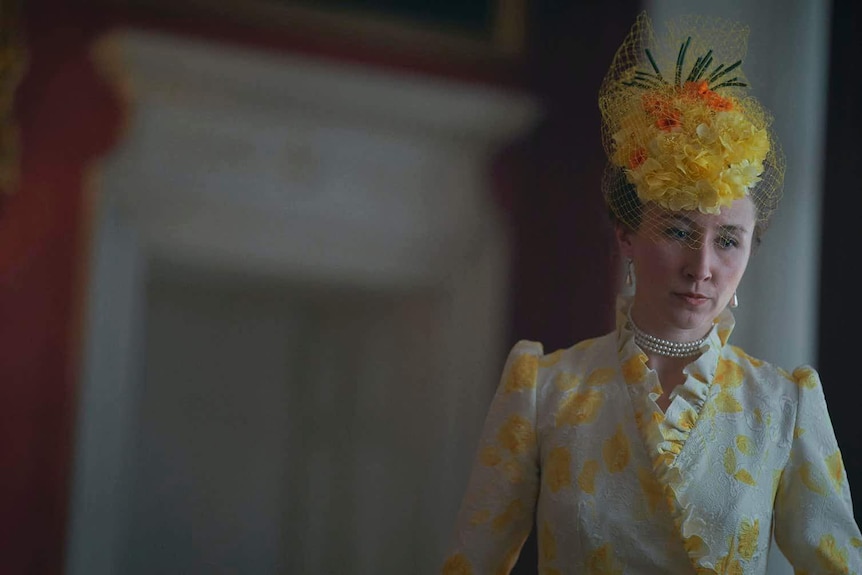 An actress in a cream dress and yellow floral headpiece