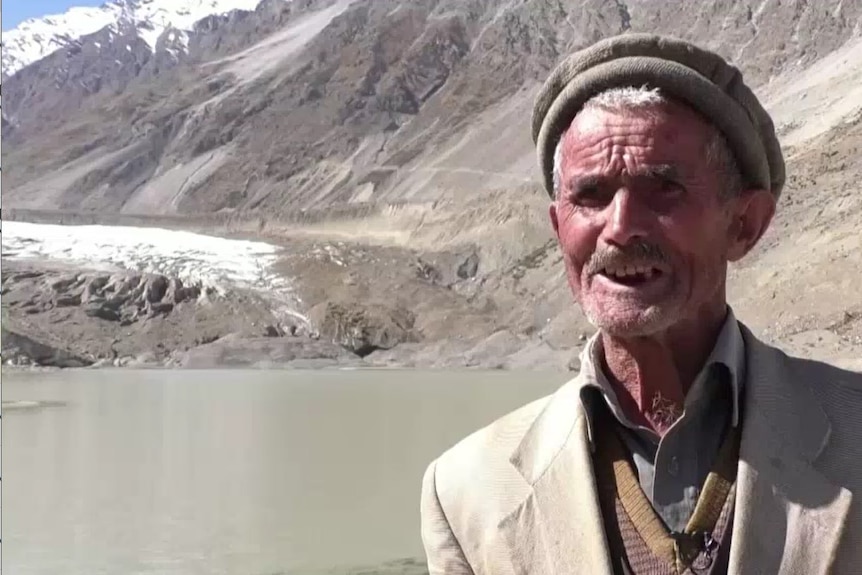 Close up of Pakistani man with glacial lake in the background.