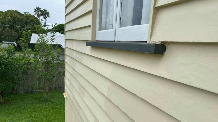 The side of a house with different coloured paint along the weatherboards.