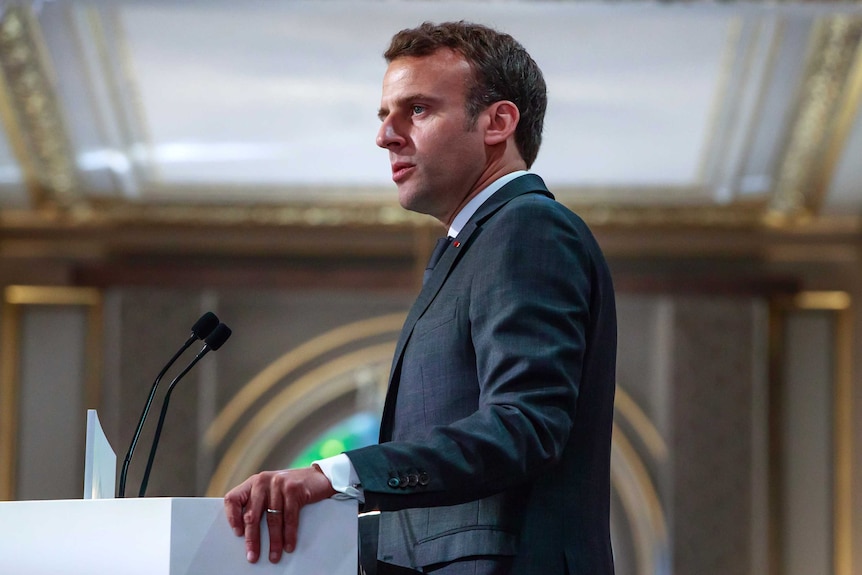French President Emmanuel Macron speaks at a podium.