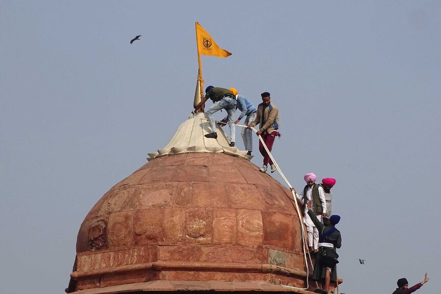 Sikhs hoist a Sikh religious flag on a minaret dome of the historic Red Fort monument.