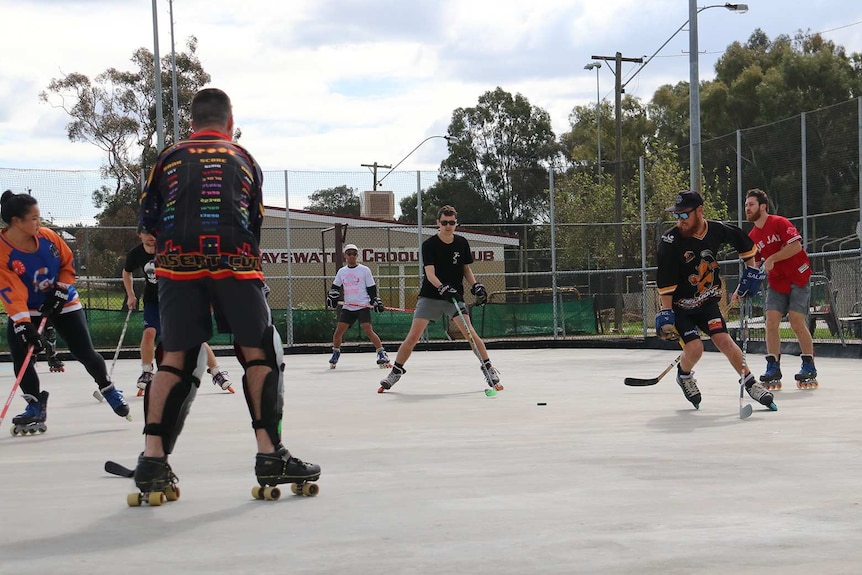 People playing roller hockey on a concrete court at a bowling club.
