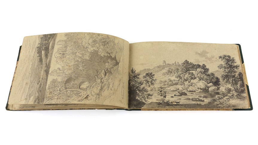An old book with a landscape sketch on each page.