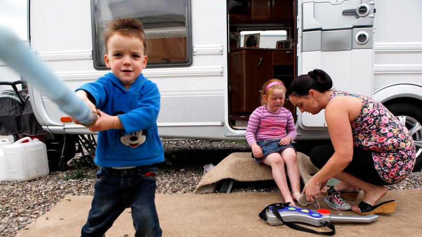 A family gather outside their caravan on the Dale Farm Traveller camp