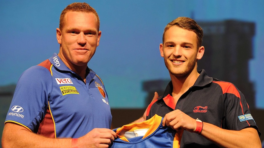 Brisbane coach Justin Leppitsch presents James Aish with a Lions guernsey at the AFL Draft.