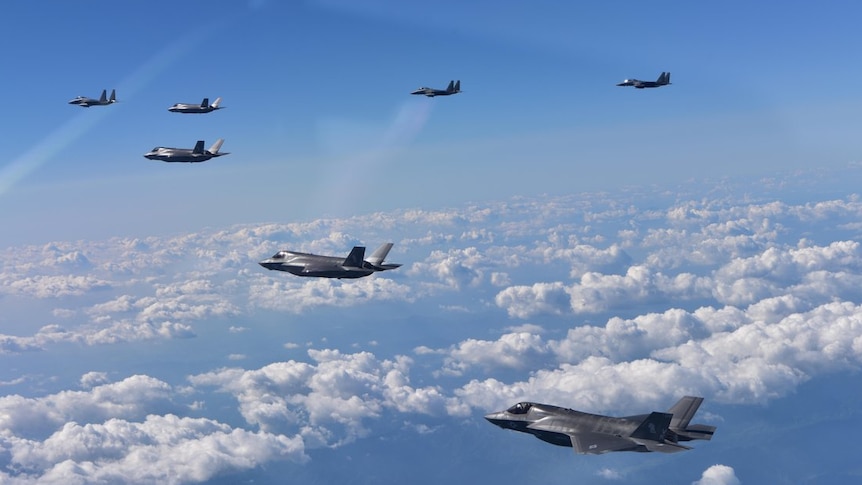 Six bomber planes fly through the clouds.