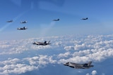 Six bomber planes fly through the clouds.