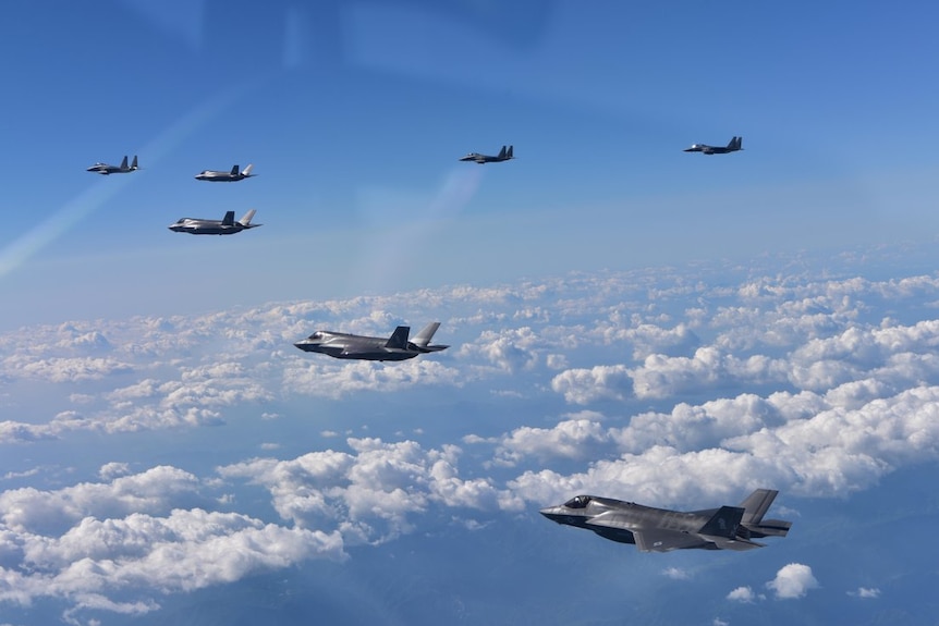 Six bomber planes fly through the clouds.