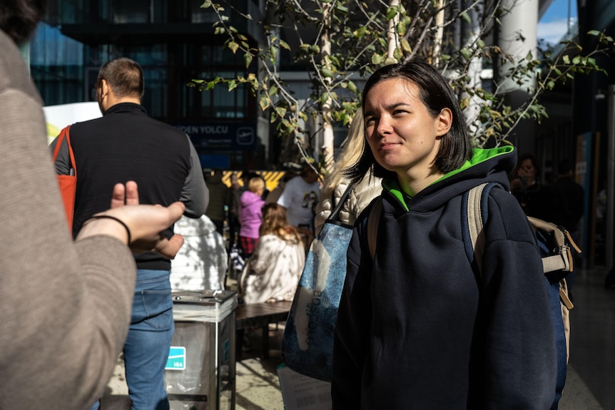 A young woman with a black bob stands in the sun outside the Istanbul airport.  