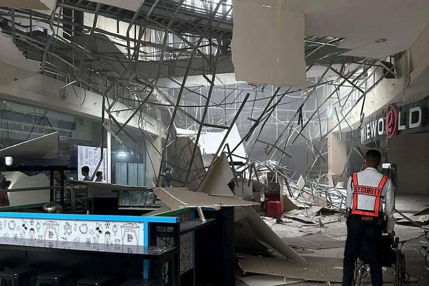 inside of a shopping mall where the roof has caved in with construction debris everywhere