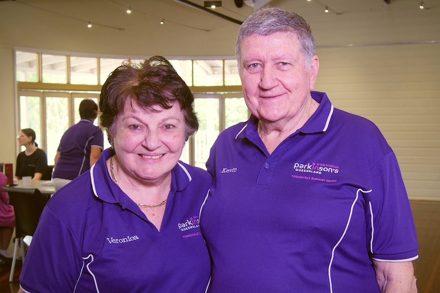 A smiling man and woman in purple Parkinson's Queensland shirts 