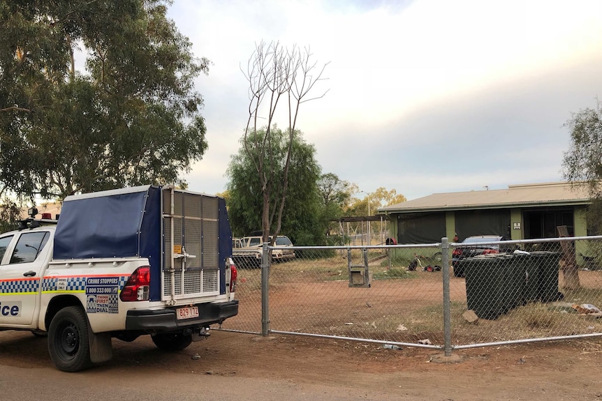 Police wagon parked in front of a fenced camp.