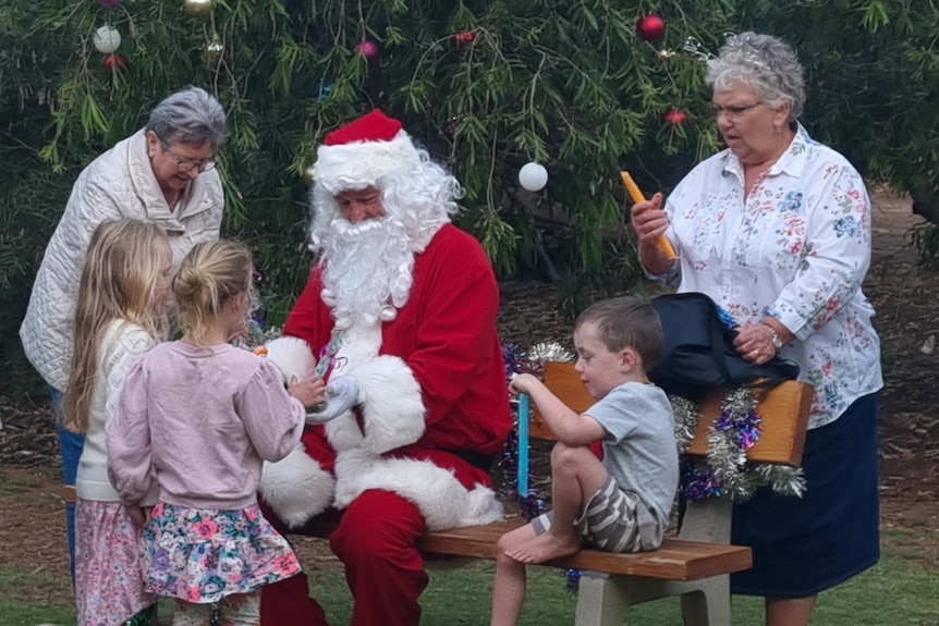 Father Christmas sits on bench with kids