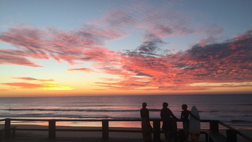 Boys standing watching the ocean at sunrise