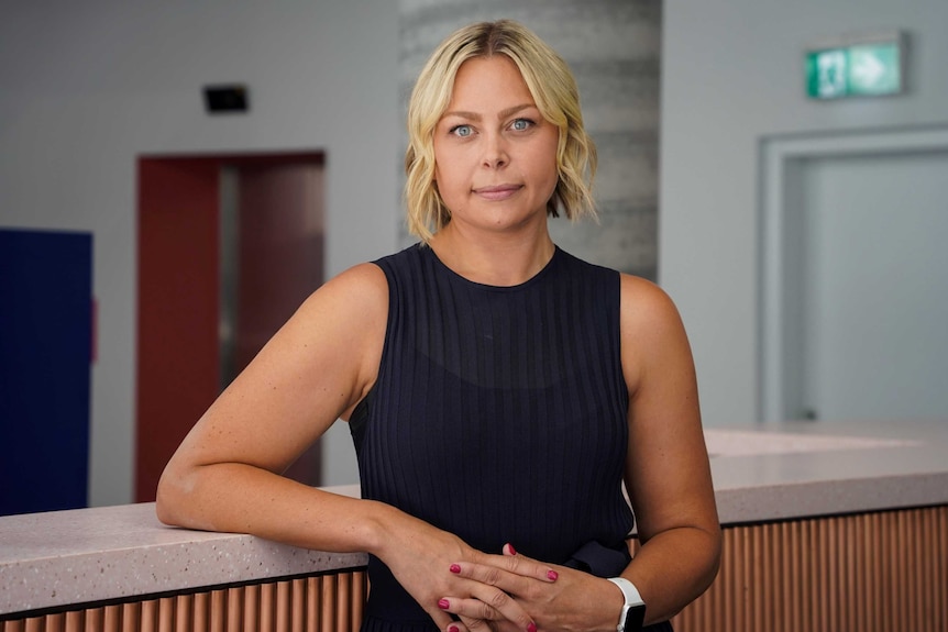 A woman in her 30s with blonde hair staring down the barrel of the camera