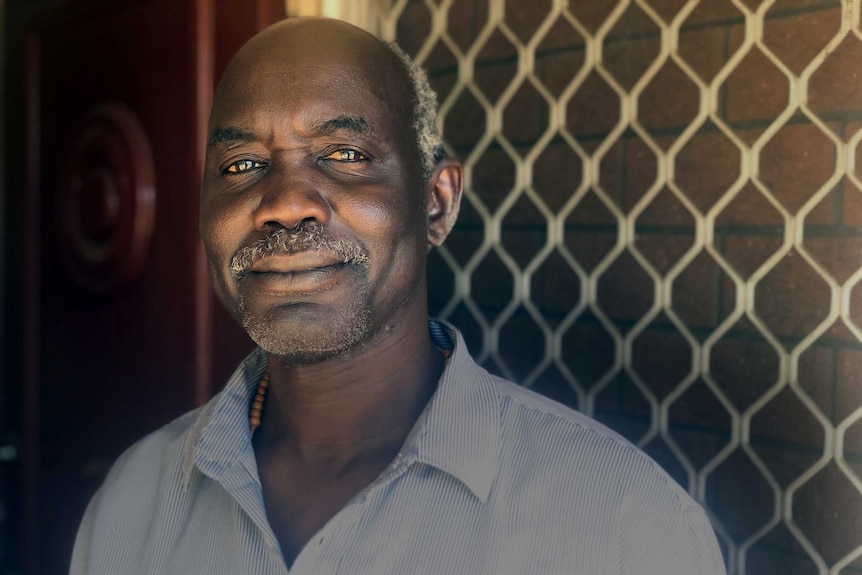 Head shot of Arou Akot standing at the door of his rented home