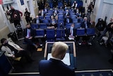 The Washington press watch from their seats as Donald Trump leaves the lectern after delivering a speech