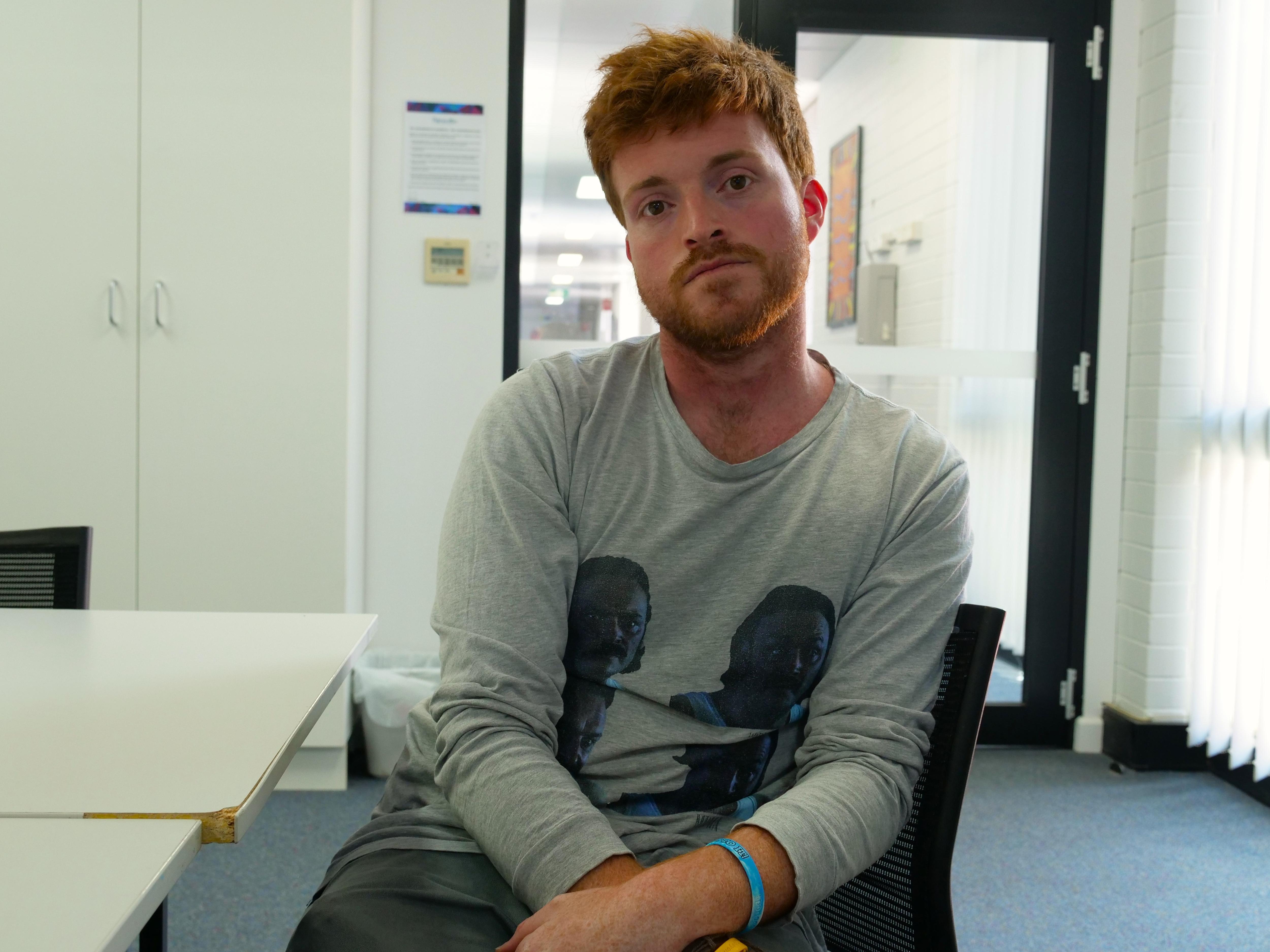 I man sitting in an office looking somberly at the camera.