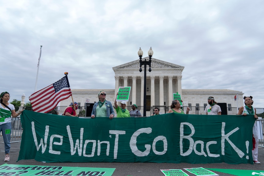 A green and white banner reads: "we won't go back." 