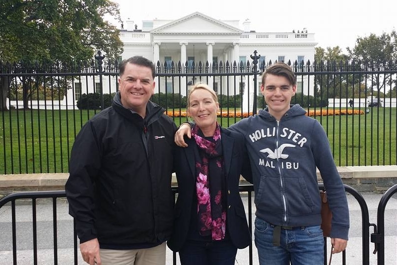 Three people stand in front of the white house