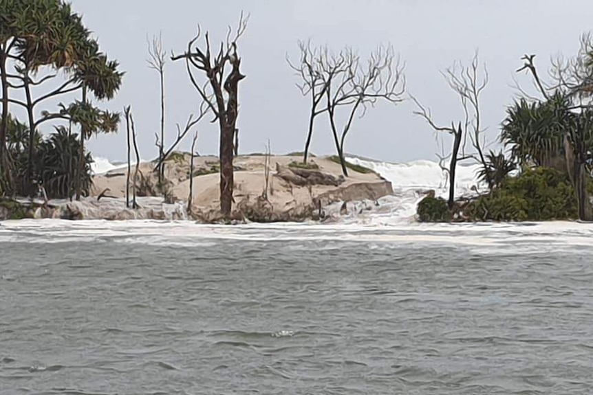 Swell breaks through sandy bank of an island