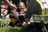 A protester tackles Jason Kessler into a bush.