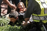 A protester tackles Jason Kessler into a bush.