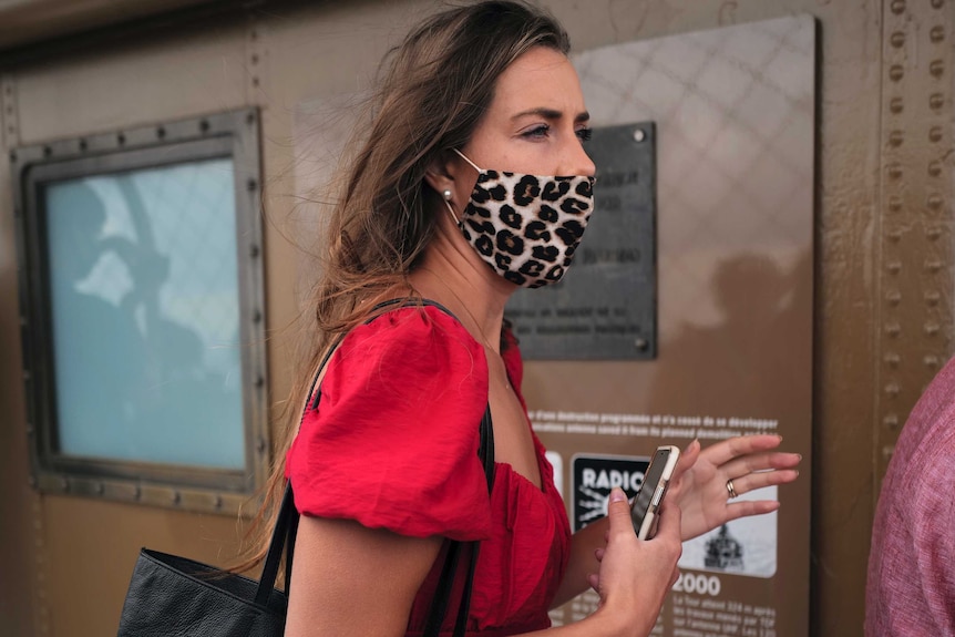 A woman wears a leopard print face mask.