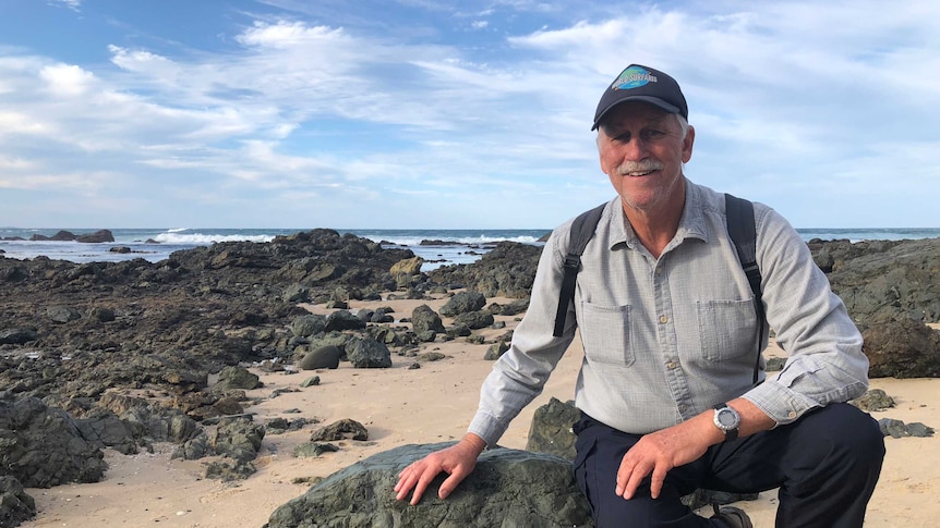 University of Newcastle Professor Ron Boyd sitting on volcanic rock at Shelly Beach