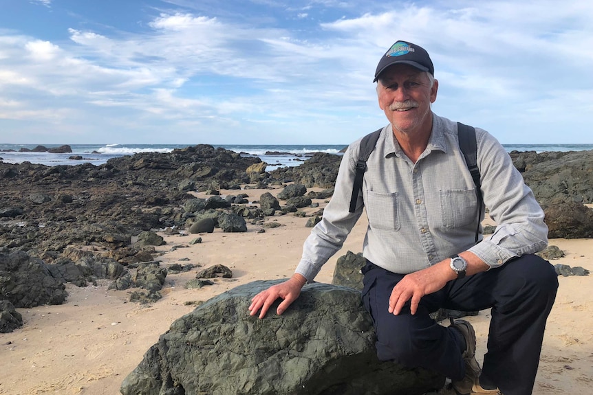 University of Newcastle Professor Ron Boyd sitting on volcanic rock at Shelly Beach