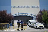 You view a roadblock to a blue and grey building with the words 'Palacio de Hileo' written on it.