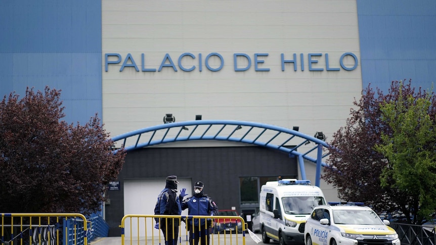 You view a roadblock to a blue and grey building with the words 'Palacio de Hileo' written on it.