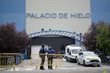 You view a roadblock to a blue and grey building with the words 'Palacio de Hileo' written on it.