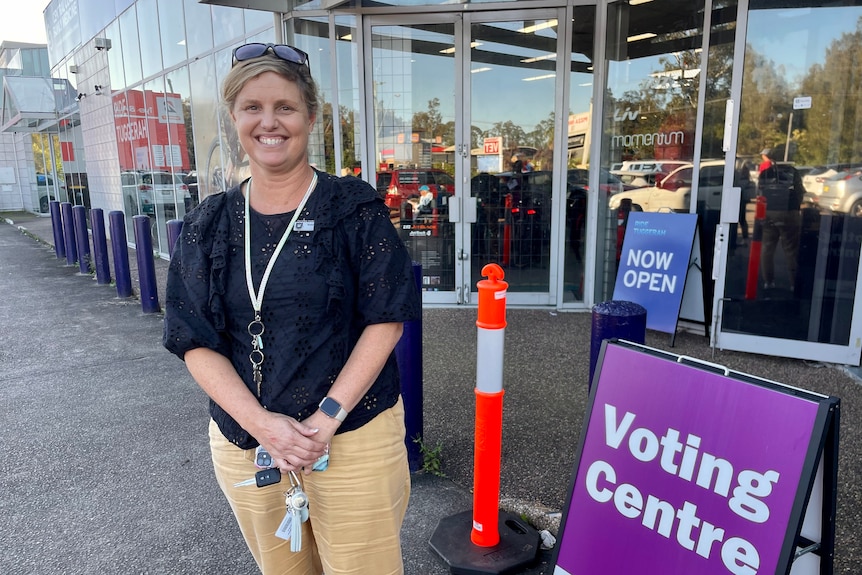 Woman stands smiling at a pre-poll station