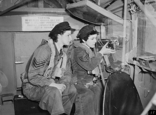 An old black and white photo of two women using a camera during pilot training.