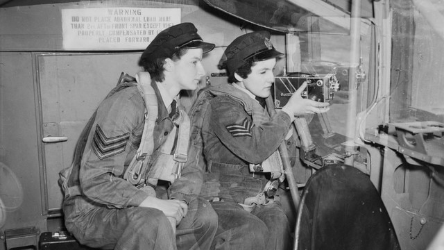 An old black and white photo of two women using a camera during pilot training.