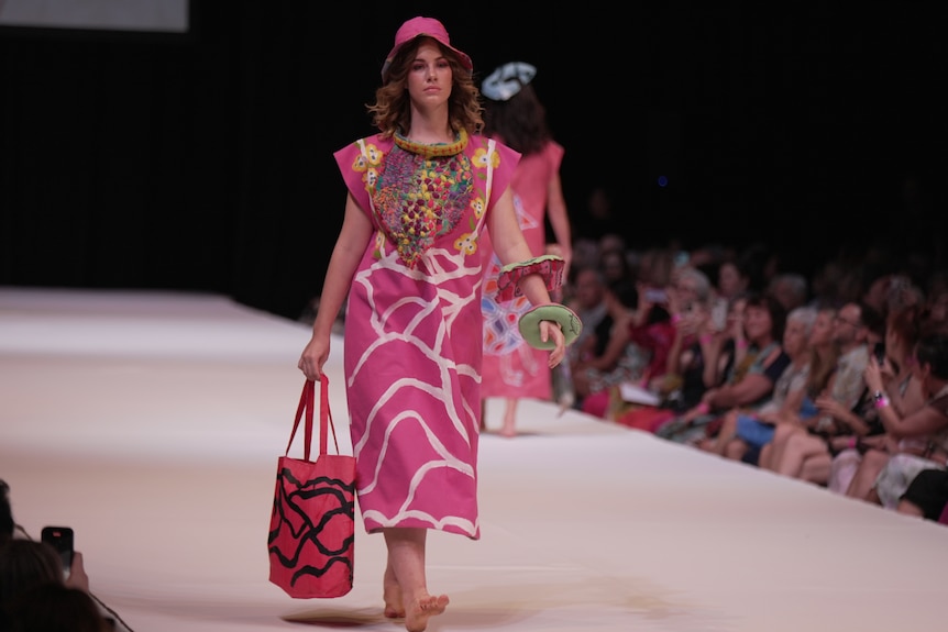 a female model wears a hot pink dress on the runway