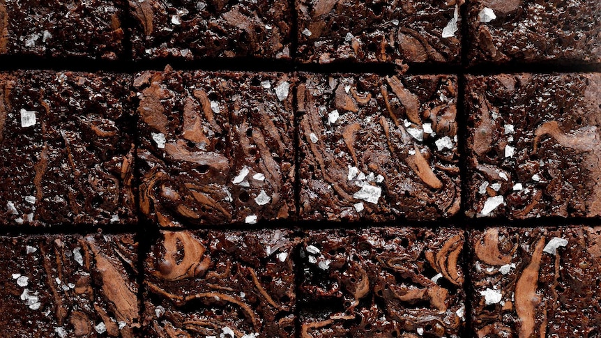 A batch of salted caramel brownies with sea salt sliced and ready to serve.