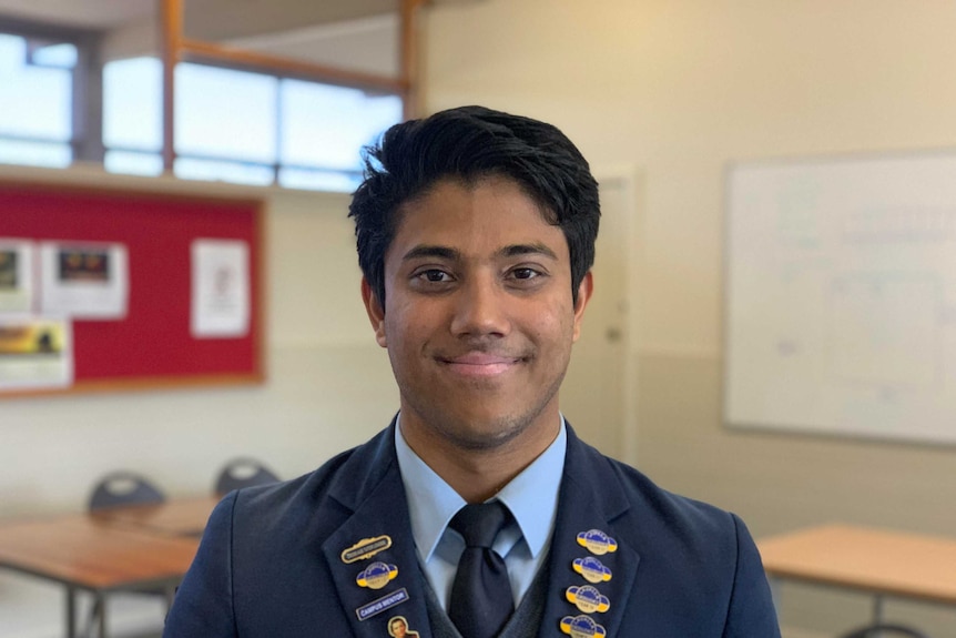 Mubasshir smiling at the camera, he is wearing a school uniform, he has dark hair and brown eyes.