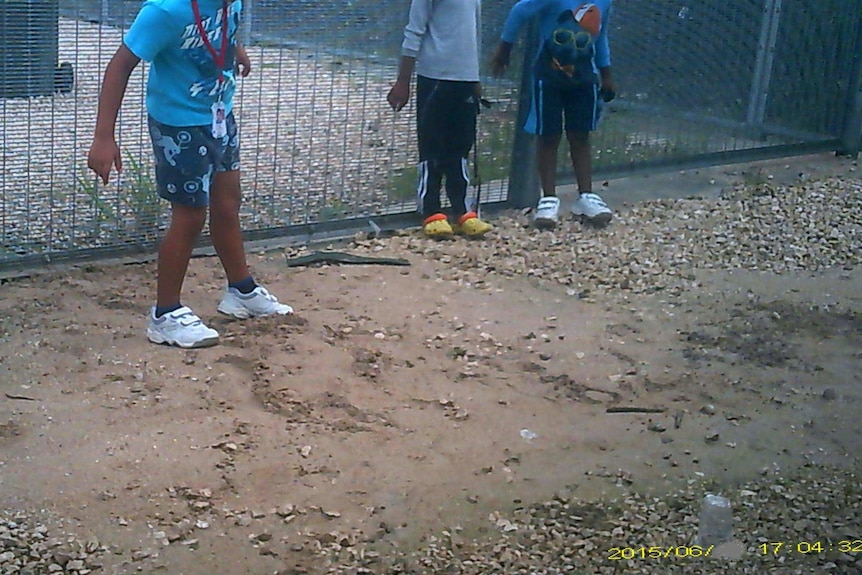 School children stand before the fence at the Nauru detention centre.