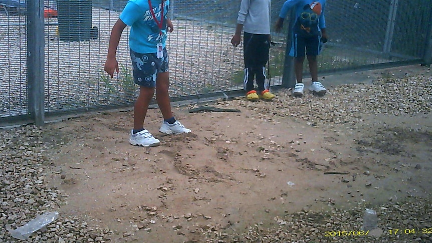 School children stand before the fence at the Nauru detention centre.