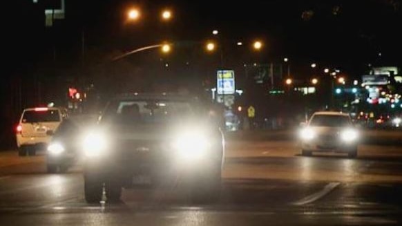 cars driving at night with headlights on at night with streetlights in background