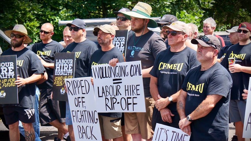 Members of the CFMEU wear union shirts and hold signs as they picket at the Wongawilli Colliery.