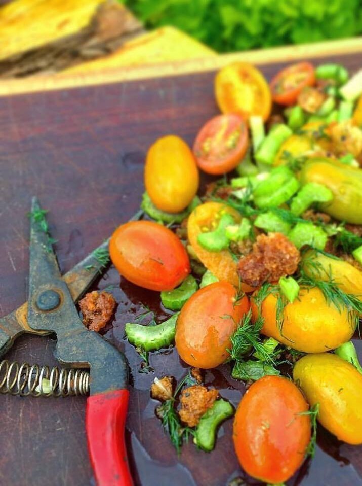 A tomato salad sits on a board next to secateurs