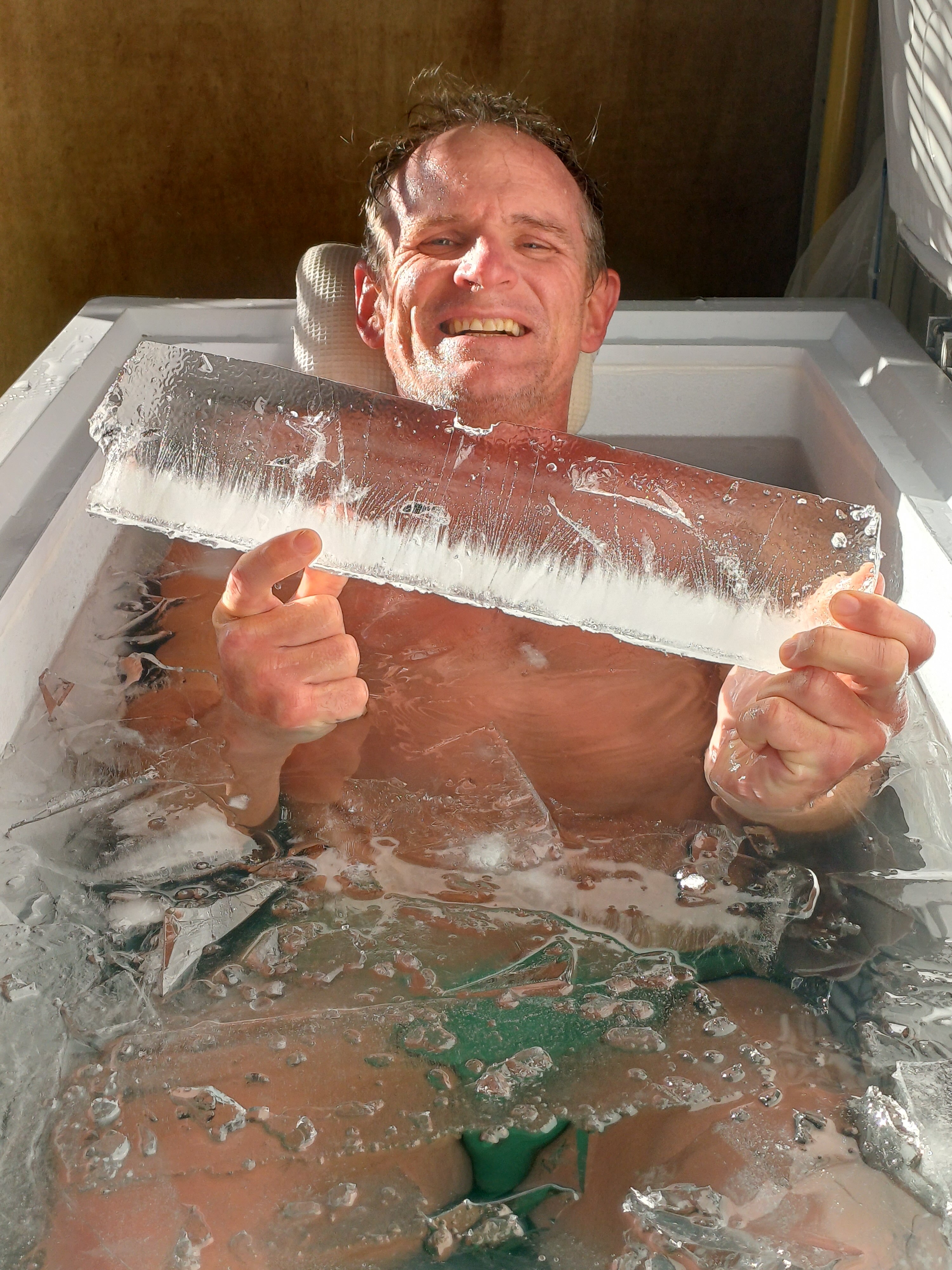 A man in an ice bath holding a chunk of ice