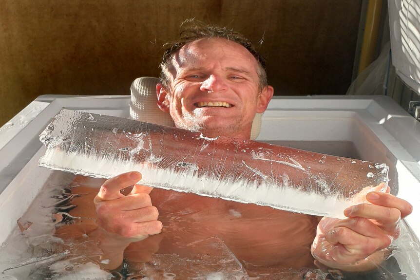 A man in an ice bath holding a chunk of ice
