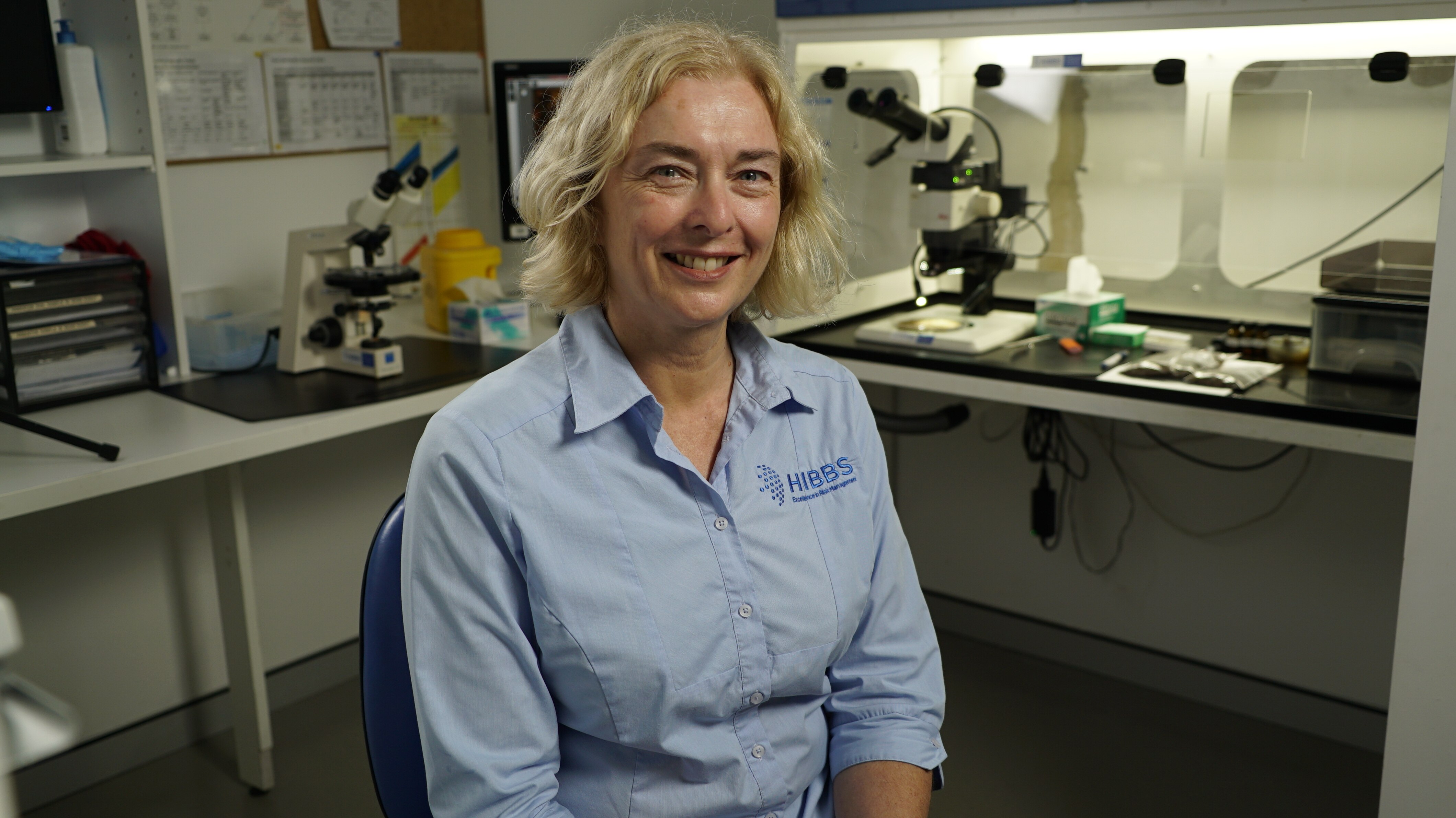 Woman in a blue shirt sitting in a laboratory.